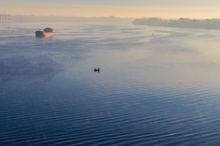 Industrial ship sailing down the river in the mist at morningの写真素材