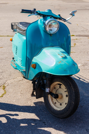 Blue retro scooter parked on city streetの写真素材