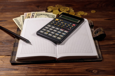 Notepad with dollars, pencil and calculator on wooden desk. Financial planning conceptの写真素材