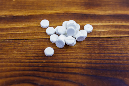 Pile of pills on the wooden background