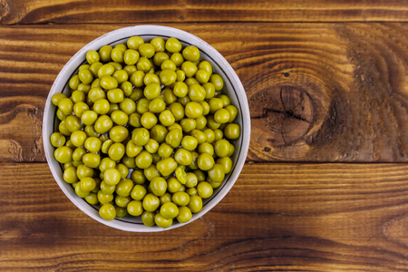 Bowl with canned green peas  on wooden table. Top viewの写真素材