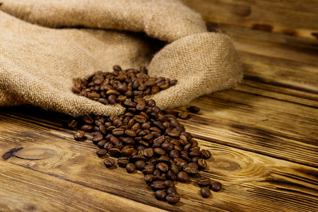 Roasted coffee beans on sackcloth on wooden tableの写真素材