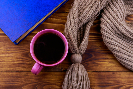 Cup of coffee, knitted scarf and book on wooden backgroundの写真素材