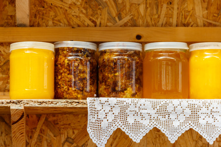 Jars of different honey varieties on a shelfの写真素材
