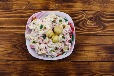 Potato salad with marinated mushrooms, sausage, onion and mayonnaise on wooden tableの写真素材