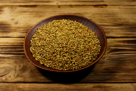 Fenugreek seeds in ceramic plate on wooden tableの写真素材