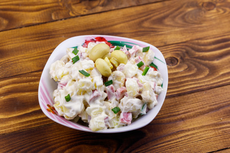 Potato salad with marinated mushrooms, sausage, onion and mayonnaise on wooden tableの写真素材