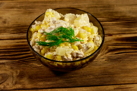 Festive salad with chicken breast, sweet corn, canned pineapple, cheese and mayonnaise on wooden tableの写真素材