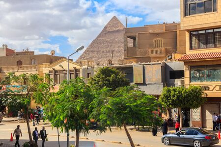 Cairo, Egypt - December 8, 2018: Busy street in the Cairo with the top of the Khafre Pyramid behind the housesのeditorial素材