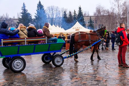 Kremenchug, Ukraine - February 17, 2018: Unknown people ride in horse cart in city park during Maslenitsa celebrationのeditorial素材