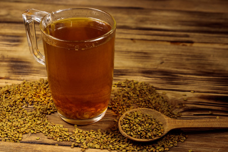 Egyptian yellow tea or Methi Dana drink and fenugreek seeds on wooden tableの写真素材
