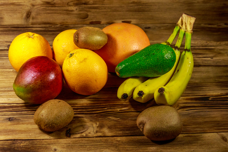 Assortment of tropical fruits on wooden table. Still life with bananas, mango, oranges, avocado, grapefruit and kiwi fruitsの写真素材