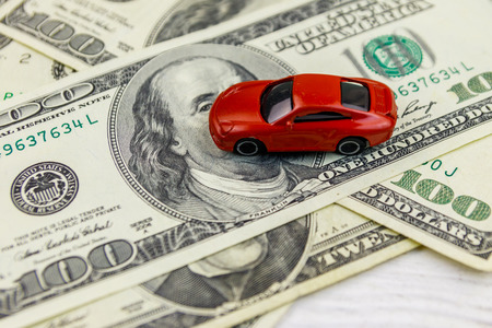 American dollars and miniature car model on white wooden background. Car loan conceptの写真素材