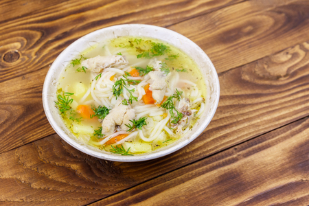 Chicken soup with noodles and vegetables on wooden tableの写真素材