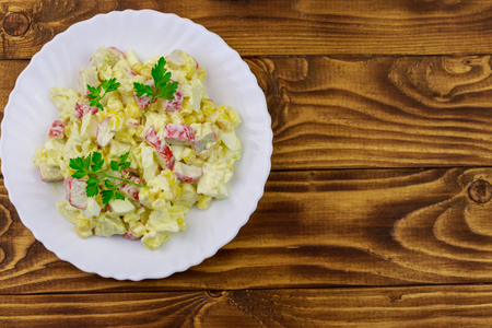 Salad with crab sticks, sweet corn, chinese cabbage, eggs and mayonnaise on wooden tableの写真素材