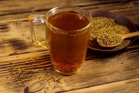 Egyptian yellow tea or Methi Dana drink and fenugreek seeds on wooden tableの写真素材