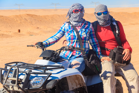 Young couple in safari trip through egyptian desert driving ATV. Quad bikes safari in the desert near Hurghada, Egyptの写真素材