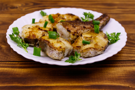 Roasted pollock in white plate on a wooden tableの写真素材