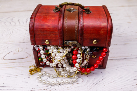 Vintage treasure chest full of jewelry and accessories on white wooden background