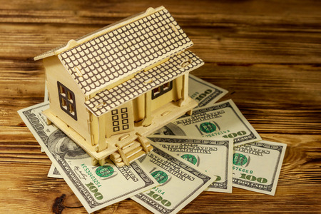House model and U.S. one hundred dollar bills on wooden background. Property investment, home loan,...