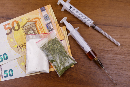 Different type of drugs: cocaine, heroin syringe and dried cannabis and euros on a table. Drug use, drug trafficking, crime and addiction conceptの写真素材