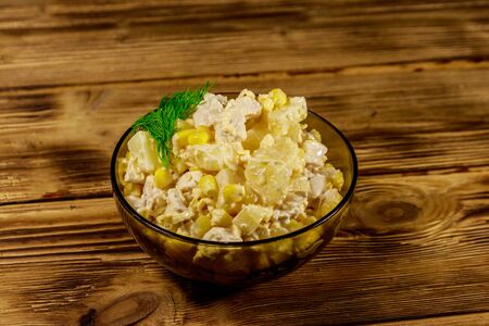 Festive salad with chicken breast, sweet corn, canned pineapple, cheese and mayonnaise on wooden tableの写真素材