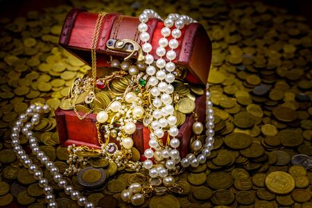 Vintage treasure chest full of gold coins and jewelry on a background of golden coinsの写真素材