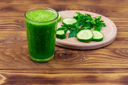 Glass of green detox smoothie of cucumber and parsley on a wooden tableの写真素材