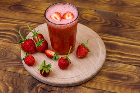 Glass of fresh strawberry smoothie on a wooden tableの写真素材