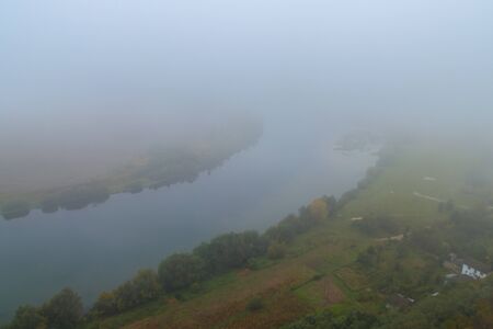 View of the Dniester river covered with a thick morning mist in autumn time