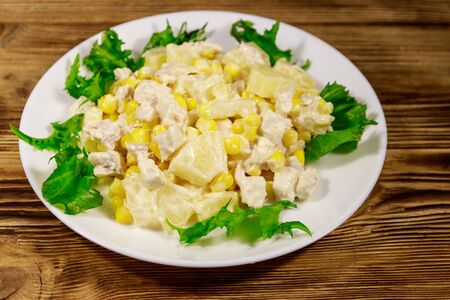 Festive salad with chicken breast, sweet corn, canned pineapple and mayonnaise on wooden tableの写真素材