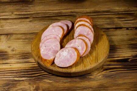 Sliced smoked sausage on cutting board on wooden tableの写真素材