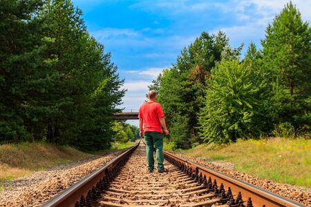 Lonely man walking on a railway trackの写真素材