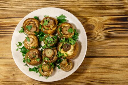 Baked mushrooms in plate on a wooden table. Top viewの写真素材