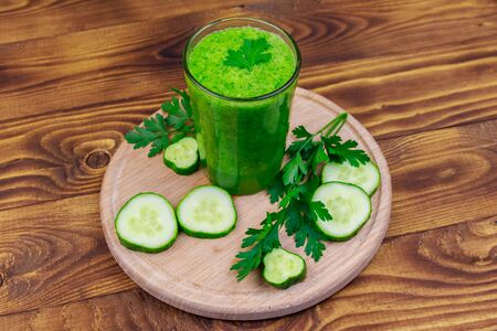 Glass of green detox smoothie of cucumber and parsley on a wooden tableの写真素材