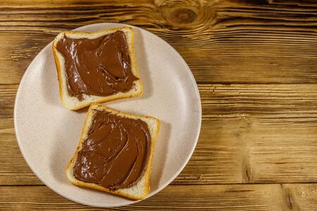Two slices of bread with delicious chocolate hazelnut spread on wooden table. Top viewの写真素材