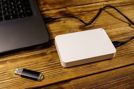 External HDD connected to laptop computer and USB flash drive on a wooden desk. Concept of data storageの写真素材
