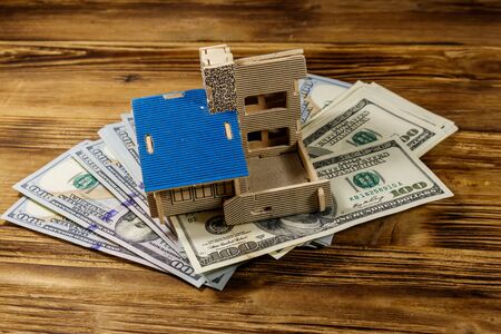 House model and U.S. one hundred dollar bills on wooden background. Property investment, home loan,...
