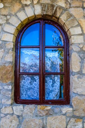 Arched wooden window in a stone wallの写真素材