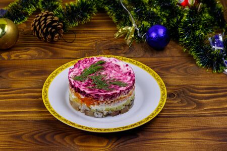 Traditional russian salad "Herring under a fur coat" (shuba) and Christmas decorations on wooden tableの写真素材