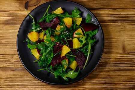 Tasty salad of fresh arugula, beetroot and oranges on wooden table. Top view. Healthy food or vegetarian conceptの写真素材
