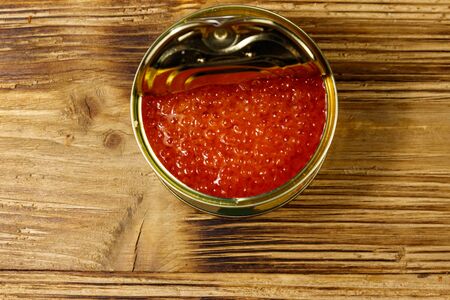 Open tin can with red caviar on wooden table. Top viewの写真素材