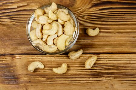 Glass bowl with raw cashew nuts on a wooden table. Top viewの写真素材
