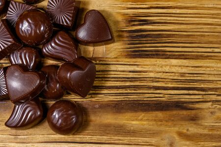 Tasty chocolate candies on wooden table. Top view, copy space