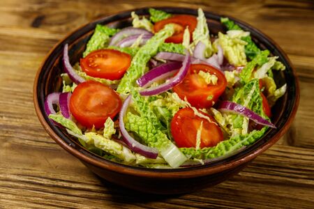 Healthy salad with savoy cabbage, cherry tomato, red onion and olive oil on wooden tableの写真素材