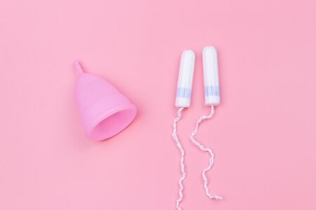 Pink reusable silicone menstrual cup and tampons on pink background. Top view. Concept of feminine hygiene, gynecology and healthの写真素材