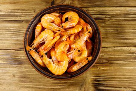 Fresh raw shrimps in a ceramic bowl on a wooden table. Top viewの写真素材