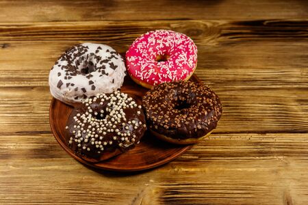 Tasty donuts on plate on a wooden tableの写真素材