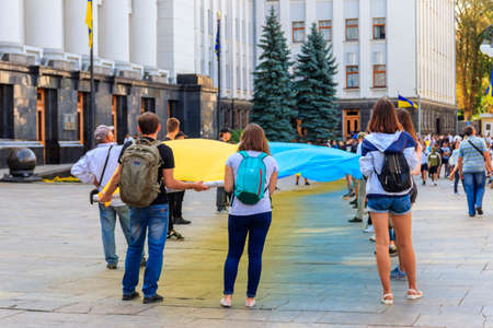 Kiev, Ukraine - August 23, 2019: People holding a huge ukrainian flag near Presidential administration during Day of Flag of Ukraine celebration in Kiev, Ukraineのeditorial素材