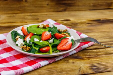 Fresh healthy salad with strawberry, spinach, walnuts and feta cheese on wooden tableの写真素材